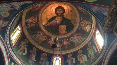 Interior of a Greek Orthodox church featuring Byzantine iconography on the ceiling